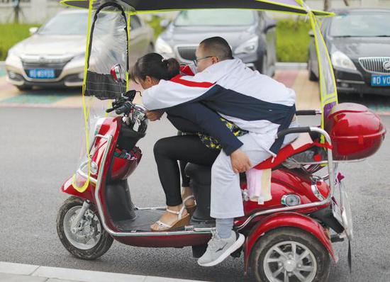 杨大连准备用电动车载孩子回家。